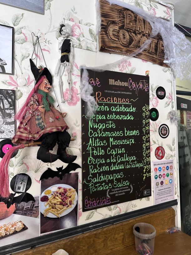 Pizarra de raciones del Bar Coyote junto al cartel de madera y una marioneta
