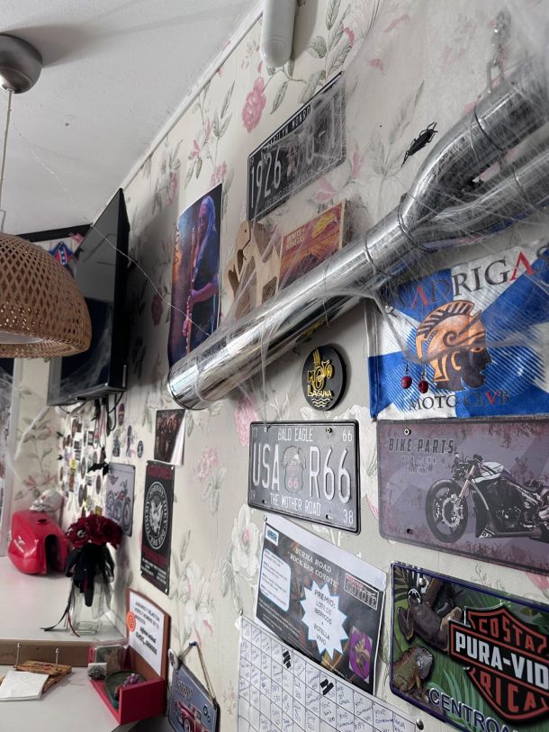 Pared del Bar Coyote con matrículas de moto y un tubo de escape