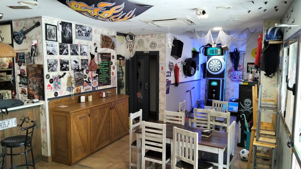 Salón del Bar Coyote con mesas y diana, donde disfrutar comidas y cenas